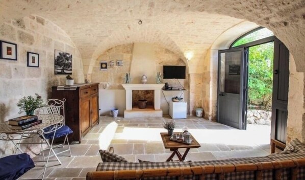Experience a blend of traditional and modern elements in this inviting space, featuring a stone archway, a wooden cabinet, and a metal-framed chair.