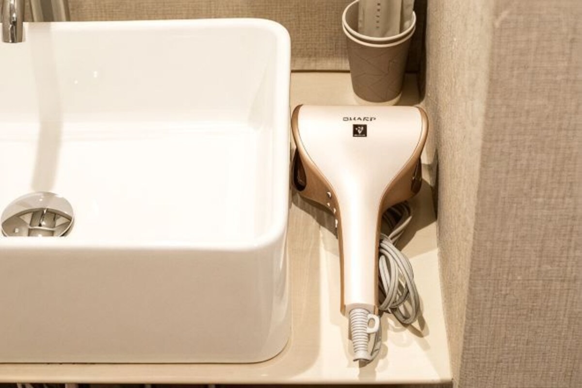 Un lavabo de salle de bain avec un sèche-cheveux posé sur un comptoir en bois.