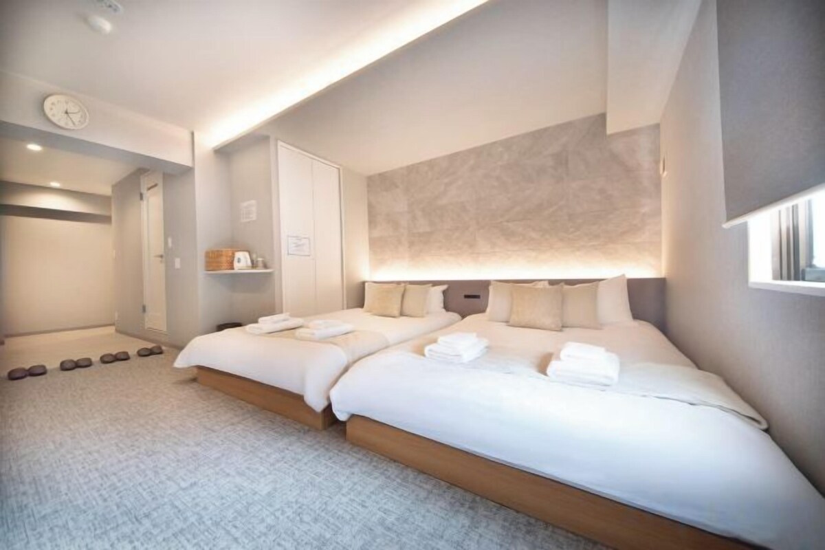 Una habitación de hotel moderna con una cama grande, mesitas de noche y una lámpara fijada a la pared.