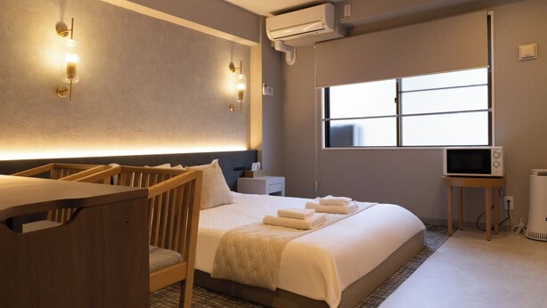Une chambre d’hôtel équipée d’un lit, d’une table de chevet, d’une télévision, d’un climatiseur et d’une fenêtre.