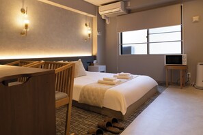 Una habitación de hotel con cama, mesita de noche, televisor, aire acondicionado y ventana.