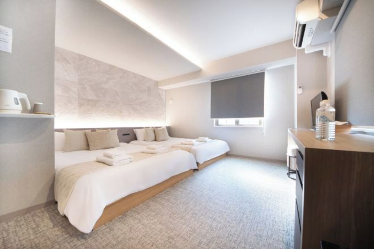 Une chambre d’hôtel moderne avec un grand lit, un petit bureau et une fenêtre.