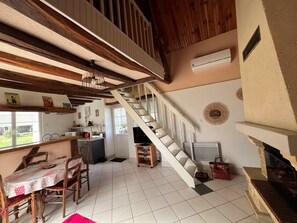 A kitchen with a dining table, chairs, a staircase, and a television. - Charming Cottage 6km from La Roche-Posay - Terrace, Garden, Baby Equipment, Pet Friendly, Wifi (La Roche-Posay)