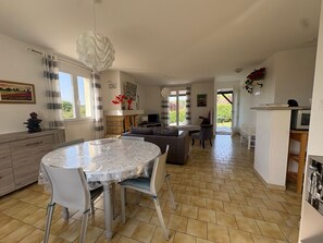 A spacious living area with a dining table, sofas, and a fireplace. - Cozy House with Garden near Thermes du Connétable - 2 BR, Fully Equipped, WiFi, Sleeps 4 (La Roche-Posay)