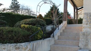 A staircase with stone steps leading up to a covered area, surrounded by greenery and trees. - Cozy House with Garden near Thermes du Connétable - 2 BR, Fully Equipped, WiFi, Sleeps 4 (La Roche-Posay)