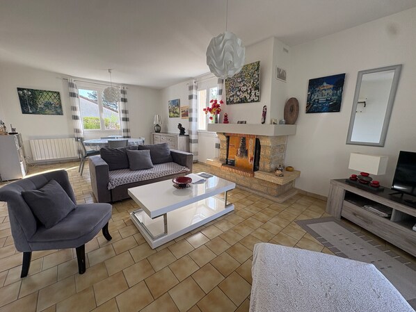 A modern living room with a fireplace, a sofa, a coffee table, and a television. - Cozy House with Garden near Thermes du Connétable - 2 BR, Fully Equipped, WiFi, Sleeps 4 (La Roche-Posay)