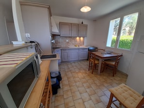 A compact kitchen with a dining area, a built-in oven, and a window providing natural light. - Cozy House with Garden near Thermes du Connétable - 2 BR, Fully Equipped, WiFi, Sleeps 4 (La Roche-Posay)