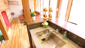 A kitchen with a stainless steel sink, wooden countertop, and a window with a view.