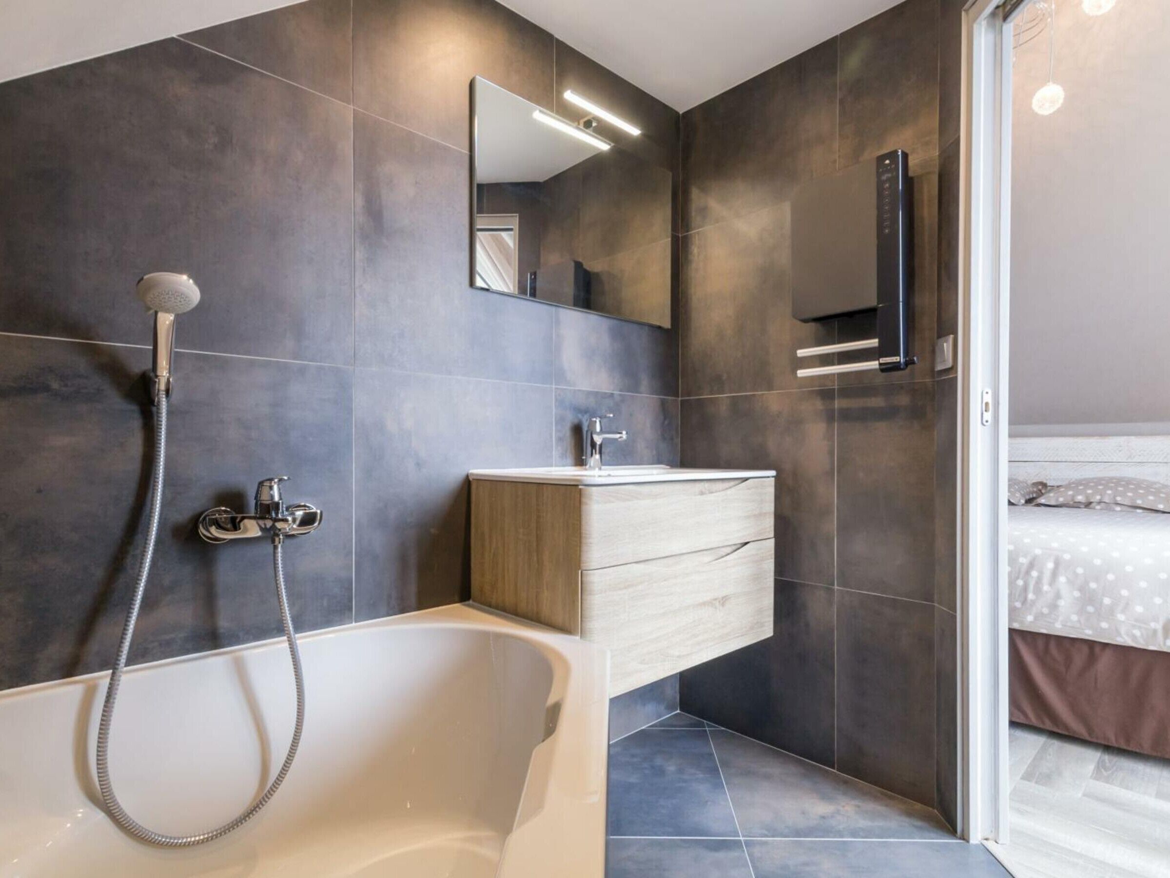 Ein modernes Badezimmer mit einer freistehenden Badewanne, einem Waschtisch mit Spiegel und einer Duschbrause.