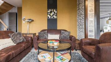 A modern living room with leather sofas, a glass coffee table, and a decorative wall piece.