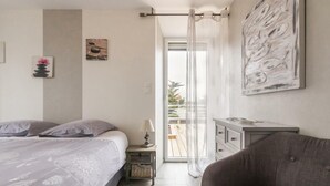 Ein Schlafzimmer mit Bett, Nachttisch, Stuhl und Blick ins Freie durch ein Fenster.