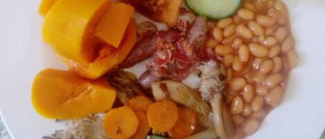 A plate of food with toast, sliced cucumbers, beans, carrots, and a slice of yellow fruit.