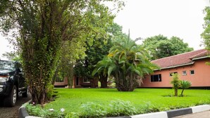 A building with a red roof, surrounded by a well-maintained garden with various plants and a large palm tree. - Fatmols lodge (Ndola)