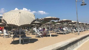 A beach with numerous sun umbrellas and lounge chairs. - Studio mit Klimaanlage und Meerblick (Porto Santa Margherita)