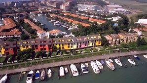 An aerial view of a marina with boats docked, surrounded by colorful buildings and a river. - Studio mit Klimaanlage und Meerblick (Porto Santa Margherita)
