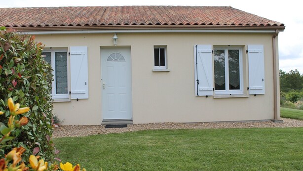Un bâtiment d’un seul étage, doté d’un toit en tuiles, d’une porte blanche et de deux fenêtres avec volets.