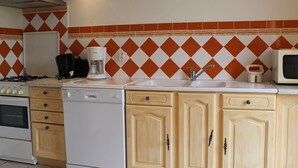 Une cuisine équipée d’une cuisinière à gaz, d’un lave-vaisselle, d’un four à micro-ondes et d’une machine à café.