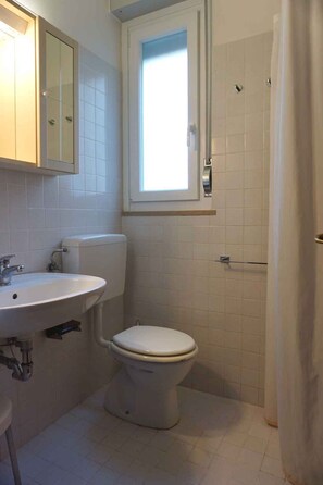 Un bagno piccolo con il water, un lavandino e una finestra sopra il water.