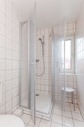 Een douche, handdoeken, zeep, toiletpapier