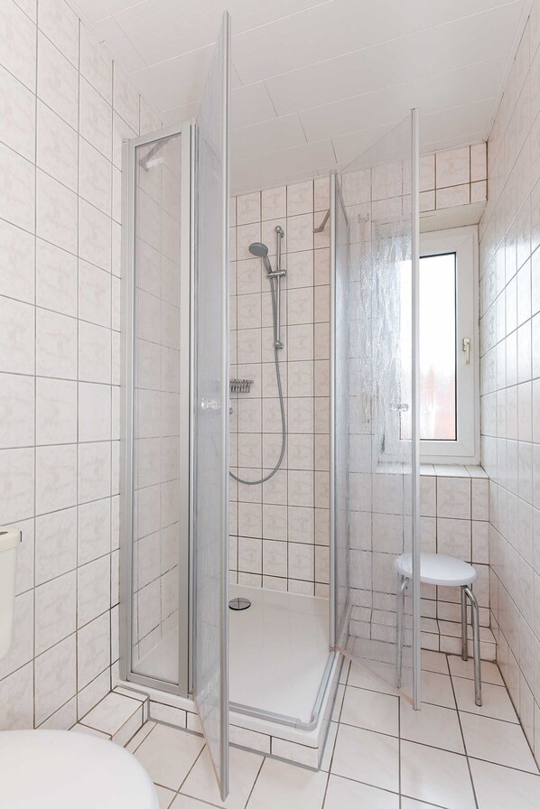 A modern bathroom with a glass-enclosed shower, a toilet, and a sink. - Ferienwohnung 2 im Ferienhaus Trautes Heim - Ferienwohnung 2 (Esens)