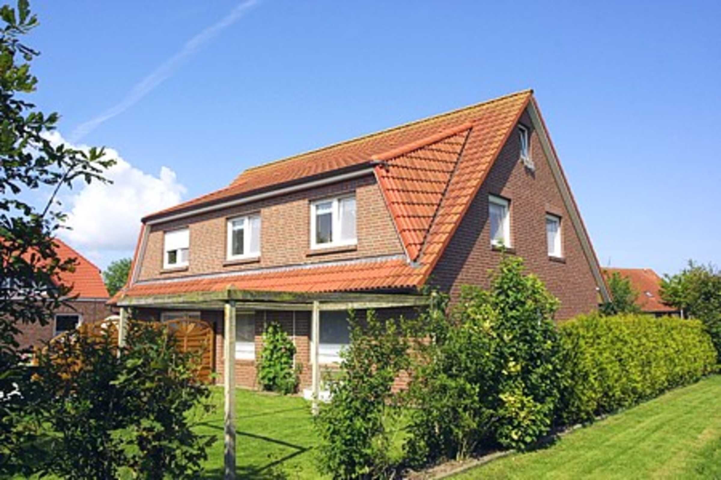 A two-story house with a red-tiled roof, a brick exterior, and a front porch.