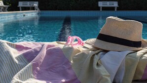A poolside area with a sun lounger, a hat, and pink swim goggles. - Holiday home with outdoor swimming pool and terrace (Porto Santa Margherita)