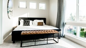 A bedroom with a large bed, a bench, and three windows. - Sky Mark Lux 2 - Seattle's Best Modern 3BD HomeTel (Seattle)