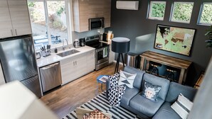 A modern kitchen with stainless steel appliances, a dining area with a blue table, and a grey sofa with patterned cushions. - Sky Mark Lux 2 - Seattle's Best Modern 3BD HomeTel (Seattle)