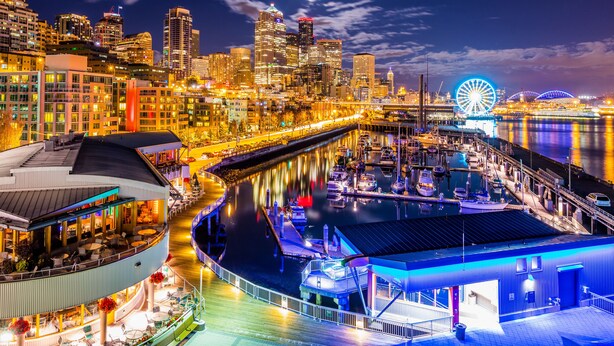 A waterfront hotel with a dining area, a pool, and a view of the city skyline at night. - Sky Mark Lux 2 - Seattle's Best Modern 3BD HomeTel (Seattle)