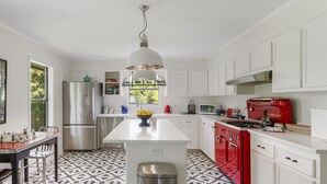 Une cuisine moderne avec des meubles blancs, des appareils en acier inoxydable et un poêle rouge.