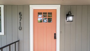 Le numéro 5710 est affiché sur une maison grise dont la porte est d’un orange vif et où l’on aperçoit une lanterne noire fixée au mur.