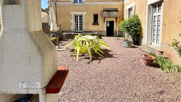 A courtyard with a building, outdoor seating, and a stone structure.