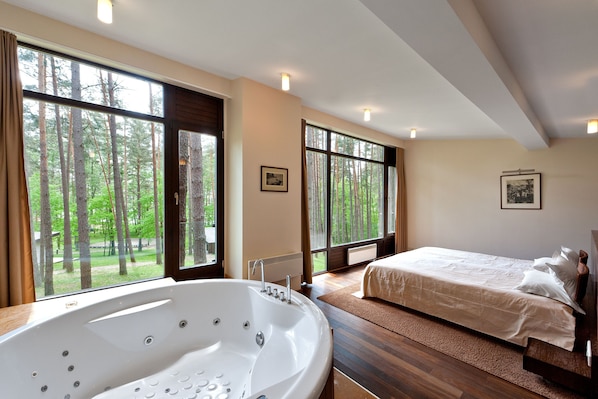 Un dormitorio con un ventanal grande, una bañera y una cama.