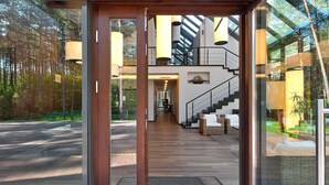 Un interior modern amb terra de fusta, una escala i una porta de vidre que dona a una zona exterior.