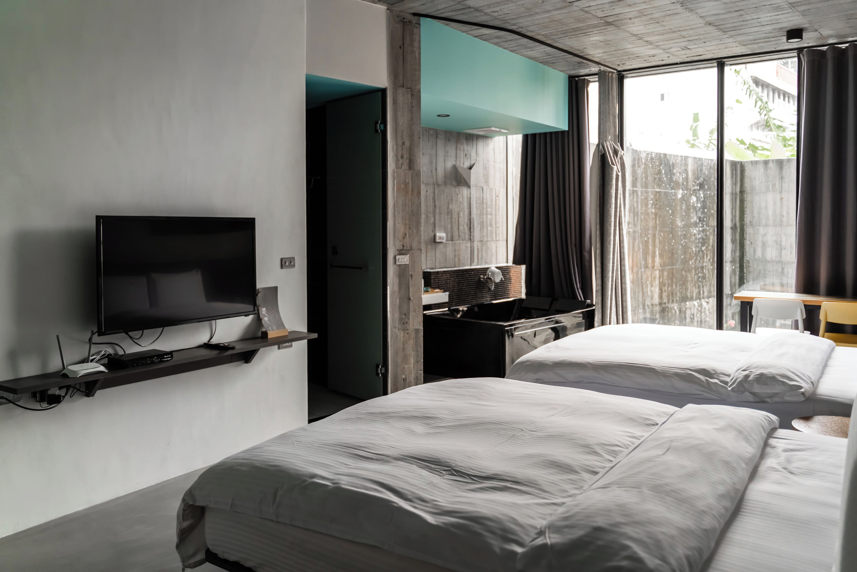Une chambre d’hôtel avec deux lits, une télévision, un bureau et une fenêtre avec des rideaux.
