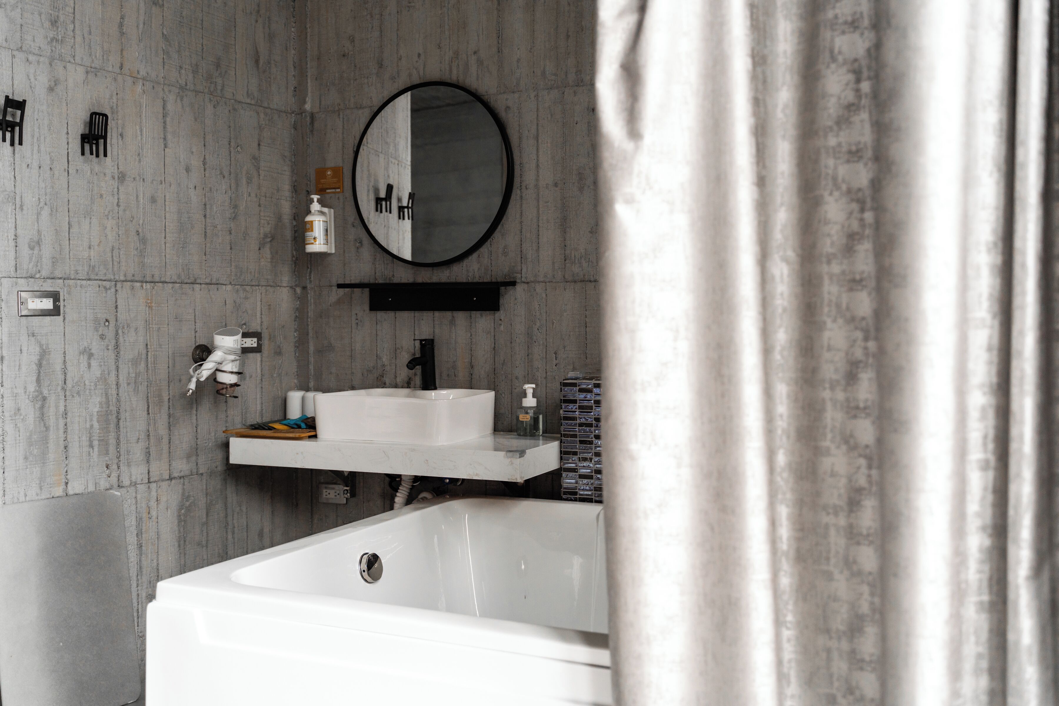 A bathroom with a bathtub, a sink, a mirror, and a shower area.