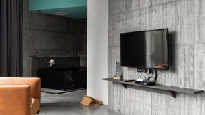A modern living room with a large flat-screen TV mounted on a wall, a comfortable sofa, and a small wooden table. - YZ Spa house (Jiaoxi)