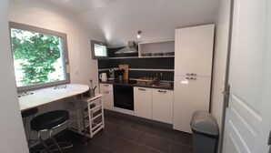 A compact kitchen with a window, a sink, a stove, and a trash bin. - Quiet cottage with garden and WIFI in La Roche-Posay (La Roche-Posay)