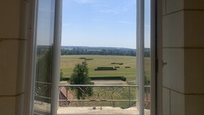 A view from a balcony with a metal railing, overlooking a large open field with trees and distant buildings. - Quiet cottage with garden and WIFI in La Roche-Posay (La Roche-Posay)