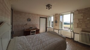 A bedroom with a bed, a desk, and a window with a view. - Quiet cottage with garden and WIFI in La Roche-Posay (La Roche-Posay)