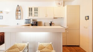 A kitchen with white cabinets, a microwave, a coffee machine, and a clock on the wall.