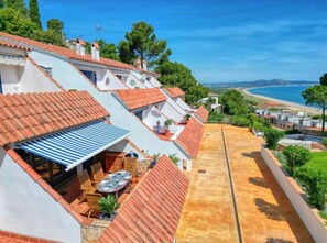 A residential area with terraced houses, a patio with outdoor furniture, and a view of the sea.