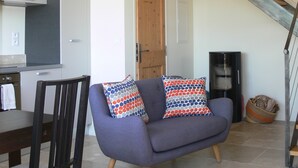 En moderne stue med sofa, træstol, et tekøkken og en trappe.