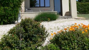 Et moderne hus med en overdækket veranda, store vinduer og en have med orange blomster.