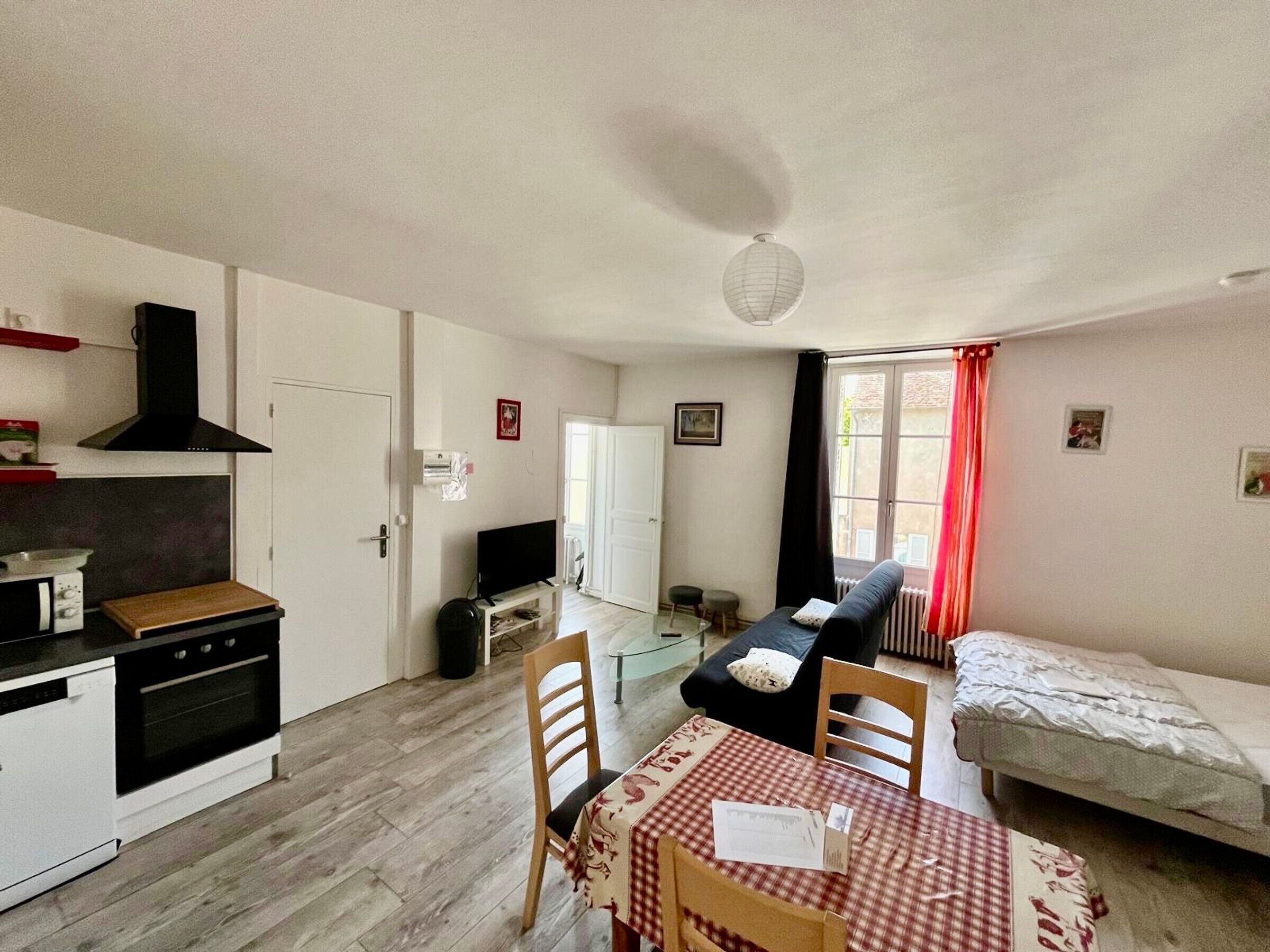 A compact living space with a kitchenette, a dining table, a sofa, and a bed.