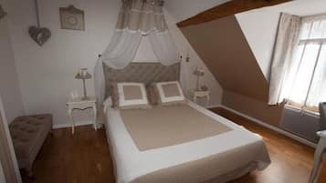 A bedroom with a bed, nightstands, a bench, a window with curtains, and a heart-shaped decoration on the wall.