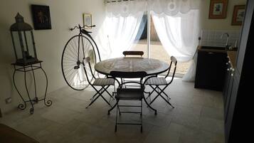 Un comedor con una mesa redonda y sillas, una bicicleta, un farol y una zona de cocina con un lavabo y armarios.