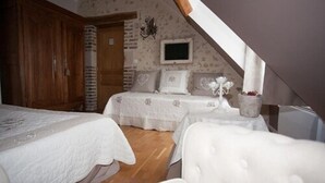 A bedroom with two beds, a wooden wardrobe, a television, and a decorative wall. - Les Jarrières (Dame-Marie-les-Bois)