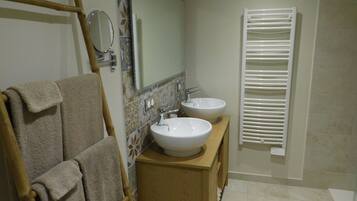 A bathroom with two sinks, a mirror, and a towel rack.