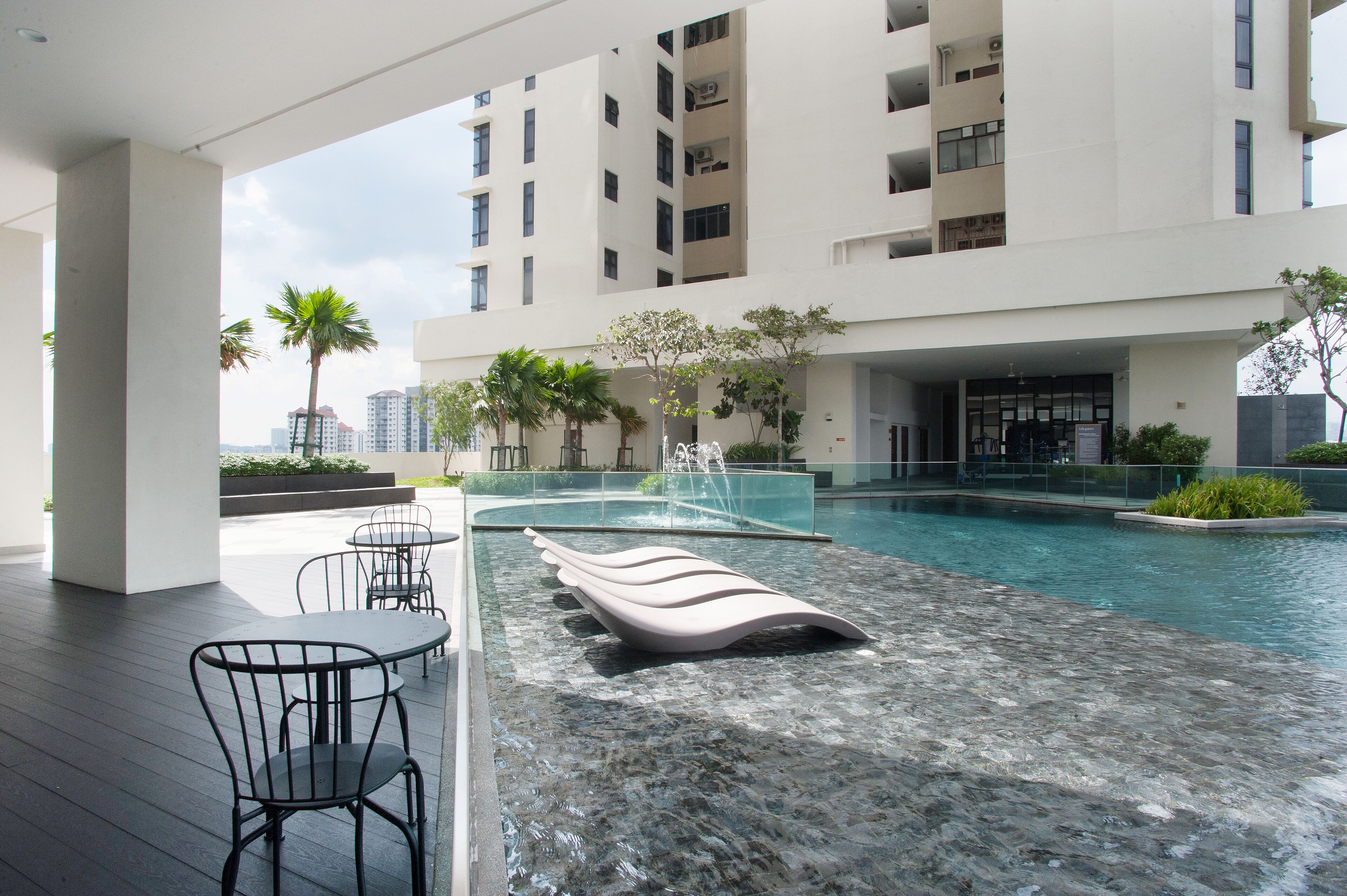 A modern outdoor pool area with a marble floor, lounge chairs, and a seating area with tables and chairs.